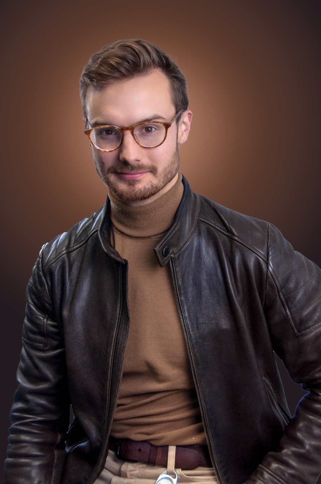 Isaac Miller in a brown leather jacket against a warm studio backdrop