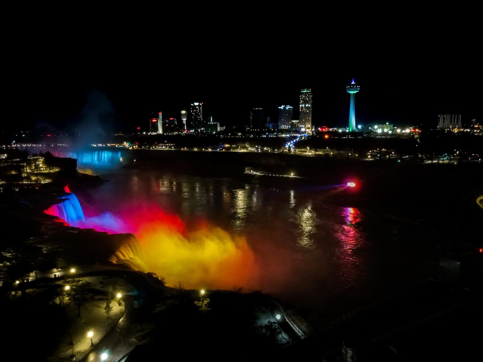 Niagara Falls lit in color at night, seen from a drone