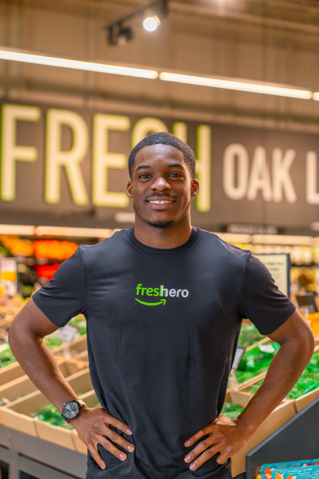 Amazon Fresh employee posing in a store aisle