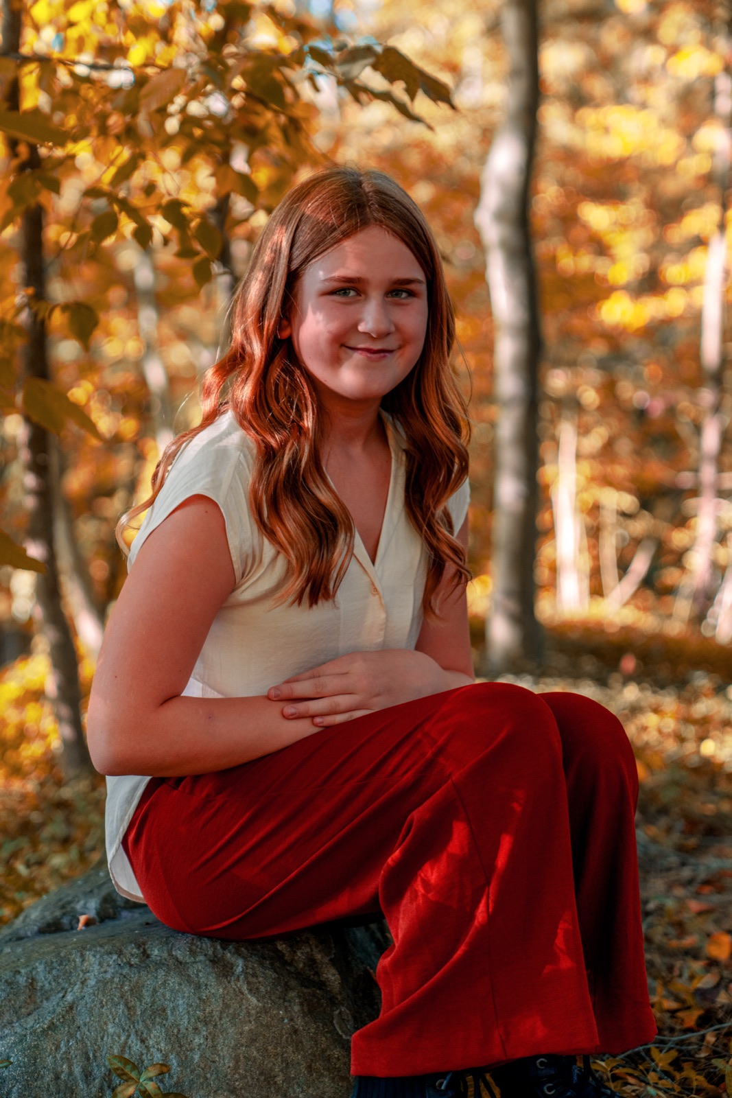 Woman in a red skirt seated among autumn trees