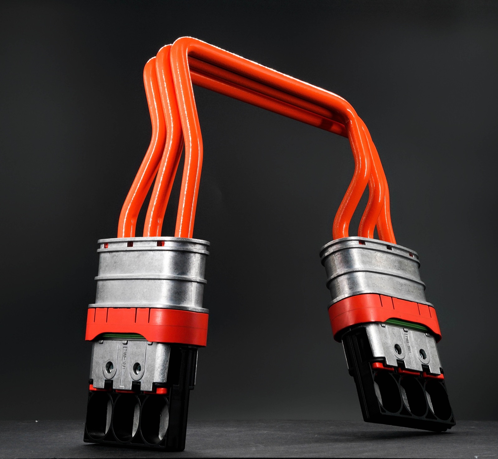 Orange high-voltage busbar connector on a dark surface