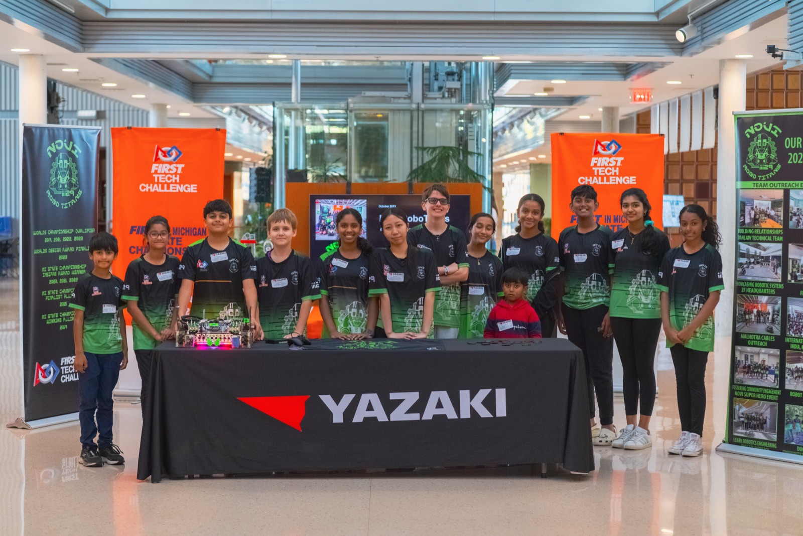 Student robotics team in matching shirts at a Yazaki table