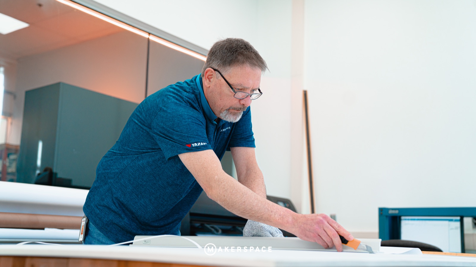 Maker trimming a large print at a cutting table