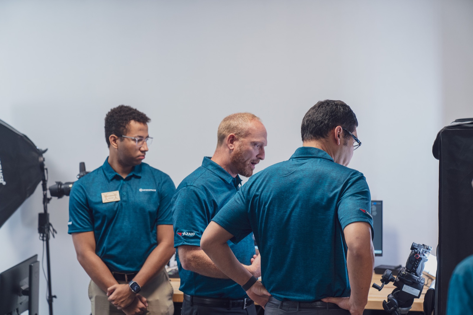 Three team members in teal polos at a camera setup
